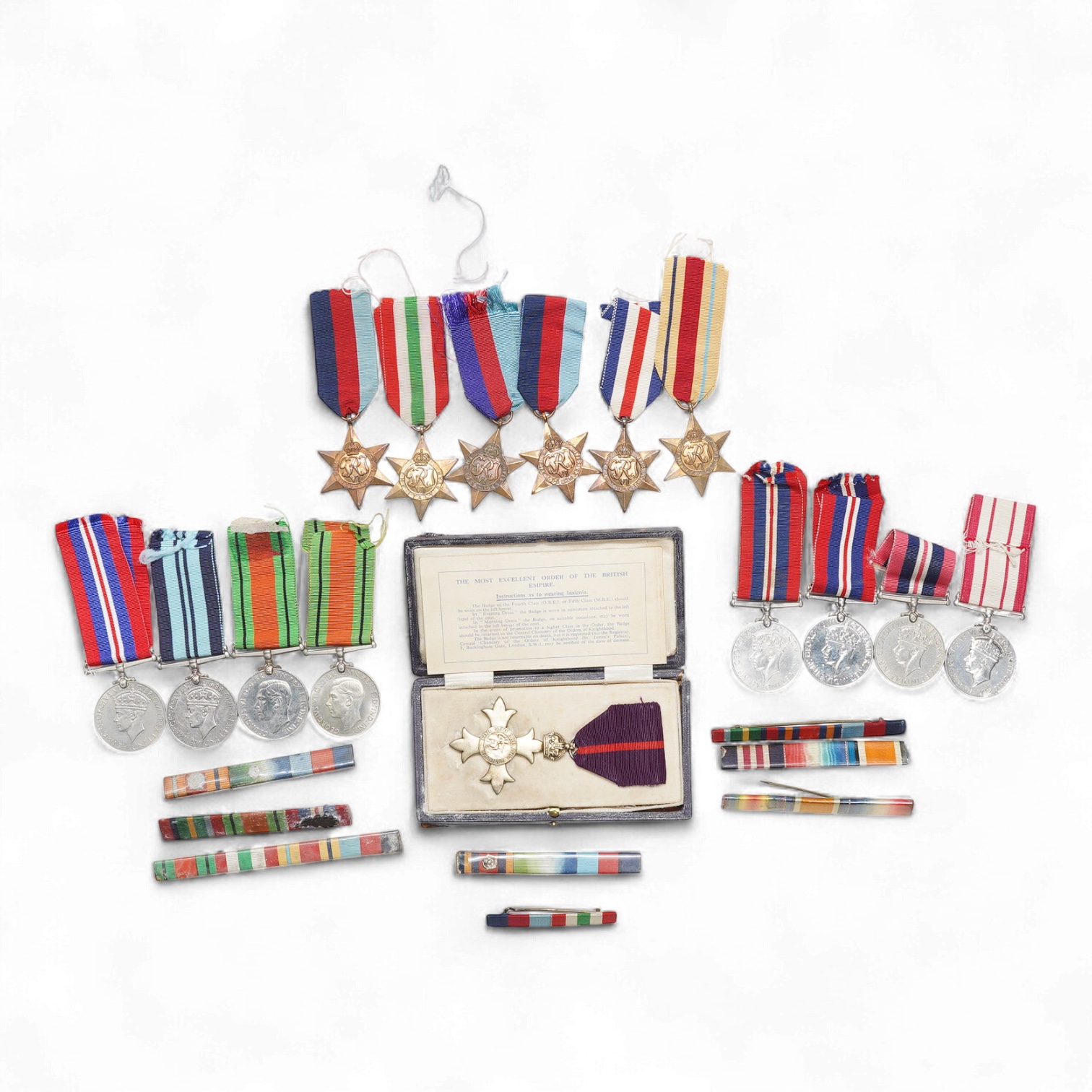 A collection of fifteen WWII military medals, all unengraved, including a cased military OBE, the Italy star, the France and Germany star, the Africa star, three 1939-1945 stars, etc., plus eight medal bars
